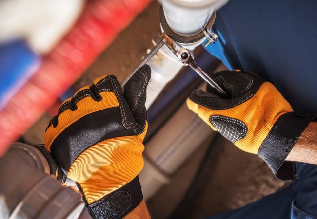 Plumber Worker Adjusting Water and Sewage System Elements Caucasian Plumber Worker Wearing Safety Gloves Adjusting Water and Sewage Residential System Elements.