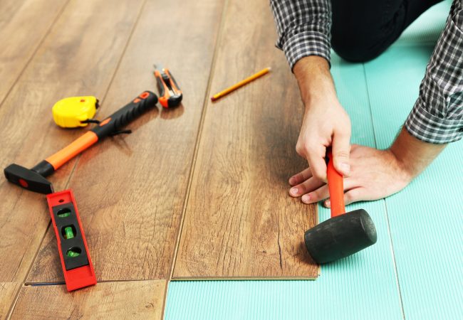 Carpenter worker installing laminate flooring in the room Carpenter worker installing laminate flooring in the room